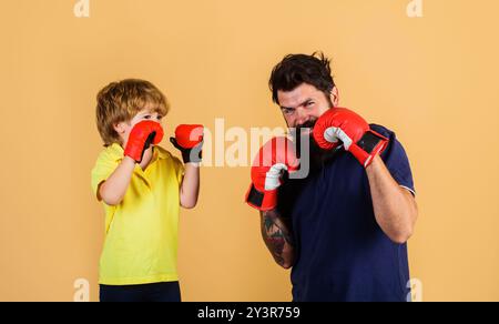 Enfant garçon sportif à l'entraînement de boxe avec entraîneur. Enfant et entraîneur dans des gants de boxe prêts pour le sparring. Petit boxeur pratiquant les coups de poing avec coach. FA Banque D'Images