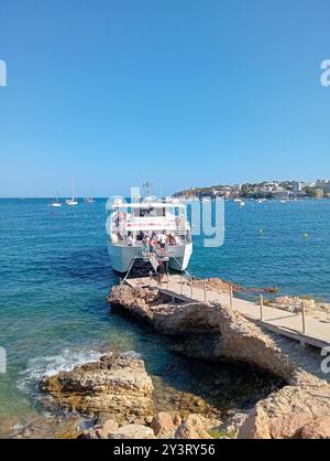 Palmanova, Espagne ; 10 août 2024 : bateau d'excursion touristique avec des touristes amarrés sur la côte rocheuse de la station balnéaire majorquine de Palmanova, sur un ensoleillé Banque D'Images