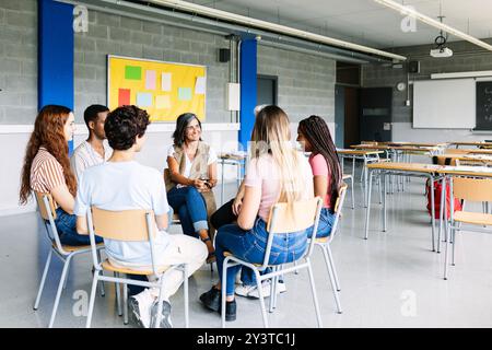 Groupe de jeunes adolescents discutant en classe avec un enseignant Banque D'Images