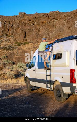 Un homme senior célibataire monte une échelle jusqu'au sommet de la camionnette Mercedes Benze dans la zone d'escalade Coulee de Frenchman. Vantage, Washington Banque D'Images