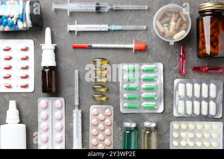 Pharmacien. Différentes pilules, seringues, flacons de gouttes médicales et ampoules sur table grise, pose à plat Banque D'Images