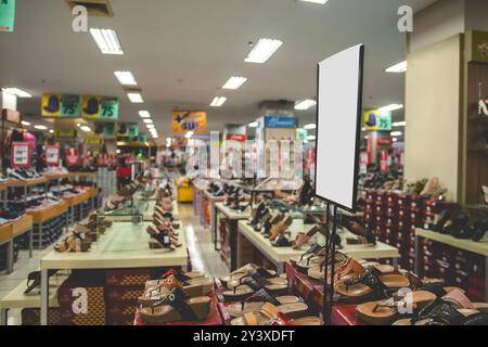 Affiches blanches vides et vierges au magasin de chaussures. Vider la signalétique vierge au centre commercial avec un arrière-plan flou. Image de signalisation pour maquette au centre commercial. COP Banque D'Images