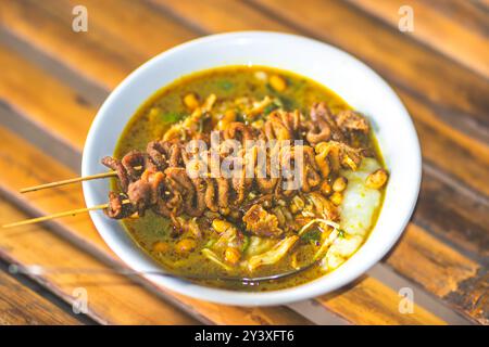 Bol de porridge de poulet servi avec des plats uniques. Porridge de poulet traditionnel avec des plats satay d'intestin de poulet, authentique traditionnel d'Indonésie Banque D'Images