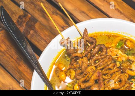 Bol de porridge de poulet servi avec des plats uniques. Porridge de poulet traditionnel avec des plats satay d'intestin de poulet, authentique traditionnel d'Indonésie Banque D'Images