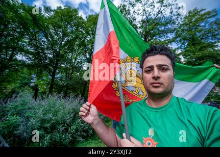 Un jeune iranien tient un grand drapeau national, pendant la commémoration. Un petit groupe d'Iraniens et de leurs partisans, très bruyants, s'est réuni face à la deuxième chambre, le siège néerlandais du parlement à la Haye, pour commémorer la mort il y a deux ans de Mahsa Amin. La jeune fille de 22 ans a été arrêtée par la police morale pour le port inapproprié de son hijab - foulard. La police a déclaré qu'elle avait subi un arrêt cardiaque lors de son interrogatoire ; ses blessures indiquaient le contraire. Elle est décédée plus tard en garde à vue. Des groupes de défense des droits humains en Iran ont déclaré à l'époque qu'au moins 150 manifestants avaient été tués. Banque D'Images