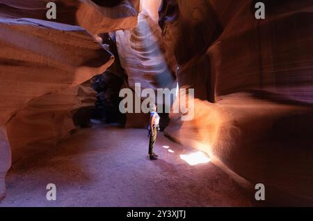 Randonneur féminin dans Slot Canyon coloré regardant le faisceau lumineux. Monument national, Utah Banque D'Images