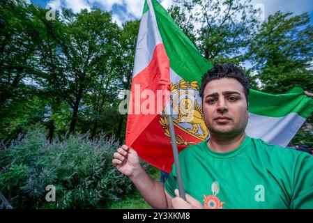 Un jeune iranien tient un grand drapeau national, pendant la commémoration. Un petit groupe d'Iraniens et de leurs partisans, très bruyants, s'est réuni face à la deuxième chambre, le siège néerlandais du parlement à la Haye, pour commémorer la mort il y a deux ans de Mahsa Amin. La jeune fille de 22 ans a été arrêtée par la police morale pour le port inapproprié de son hijab - foulard. La police a déclaré qu'elle avait subi un arrêt cardiaque lors de son interrogatoire ; ses blessures indiquaient le contraire. Elle est décédée plus tard en garde à vue. Des groupes de défense des droits humains en Iran ont déclaré à l'époque qu'au moins 150 manifestants avaient été tués. Banque D'Images