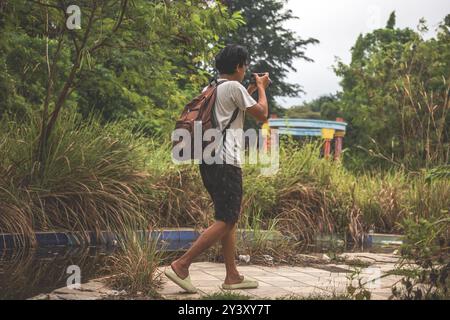 Backpacker marche seul et tenant l'appareil photo reflex numérique pour prendre des photos. Exploration sur un parc aquatique abandonné situé en Indonésie Banque D'Images