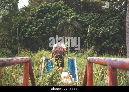 De jeunes hommes marchent autour d'un pont d'amusement situé en Indonésie. Backpacker solo explorant le parc aquatique abandonné avec sac à dos et appareil photo à la main Banque D'Images