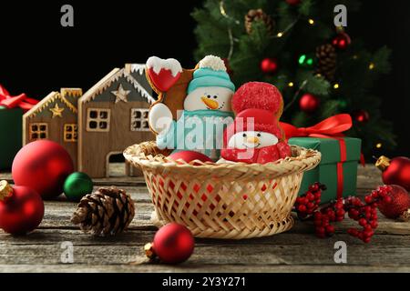 Délicieux biscuits en forme de bonhommes de neige et décor de Noël sur table en bois Banque D'Images