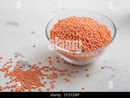Séchez les graines de lentilles orange crues dans un bol en verre sur une table lumineuse. Banque D'Images