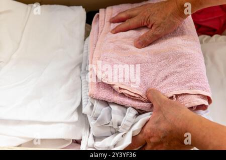 Une personne faisant la lessive à la maison mettant des vêtements séchés pliés dans un placard pour le rangement. Banque D'Images