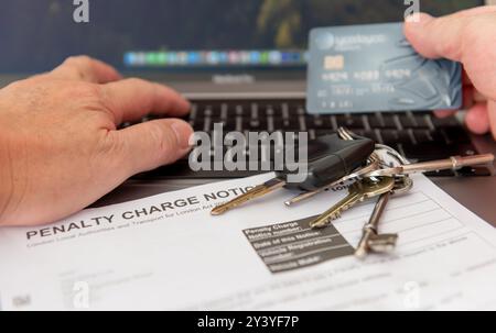 Une personne payant un avis de frais de circulation en ligne avec une carte bancaire. Banque D'Images