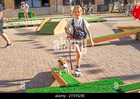 Happy Girl forme un chiot Jack Russell Terrier adulte sur un terrain d'entraînement par une journée ensoleillée. Agilité Banque D'Images
