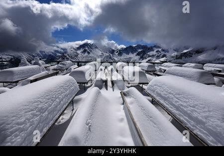 Oberstdorf, Allemagne. 15 septembre 2024. Bancs et tables recouverts de neige fraîche se dressent à la station intermédiaire de Fellhorn, haute de 1780 mètres, avec pour toile de fond les Alpes. Il a neigé une quantité inhabituellement importante pour la période de l'année dans les Alpes bavaroises. Crédit : Karl-Josef Hildenbrand/dpa/Alamy Live News Banque D'Images