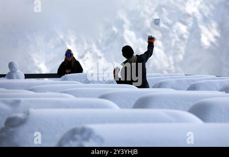 Oberstdorf, Allemagne. 15 septembre 2024. Un excursionniste jette une boule de neige entre des bancs et des tables recouvertes de neige fraîche à la station intermédiaire de Fellhorn, à 1780 mètres d’altitude. Il a neigé exceptionnellement abondamment pendant la période de l'année dans les Alpes bavaroises. Crédit : Karl-Josef Hildenbrand/dpa/Alamy Live News Banque D'Images