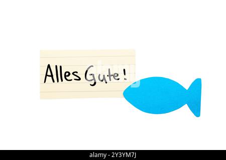 Alles Gute ! Mot de souhait allemand pour la communion sur un papier beige, écrit à la main. Isolé sur blanc. Espace libre pour le texte. Poisson en papier bleu dans le coin. Banque D'Images