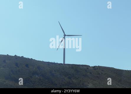 Éolienne est sur une colline avec un ciel bleu clair. L'éolienne se tient haute sur une colline verte, exploitant l'énergie renouvelable contre un ciel bleu clair Banque D'Images