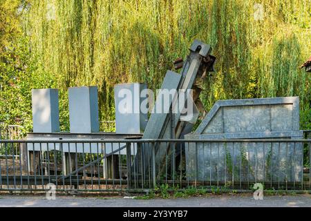 Une sculpture architecturale innovante se dresse dans un cadre de parc luxuriant, entouré d'arbres et de verdure, créant une atmosphère sereine pour les visiteurs de en Banque D'Images