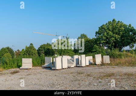 Les panneaux et les blocs de béton sont soigneusement disposés dans une zone herbeuse sous un ciel bleu clair, avec une grue visible en arrière-plan, suggérant une contestation continue Banque D'Images