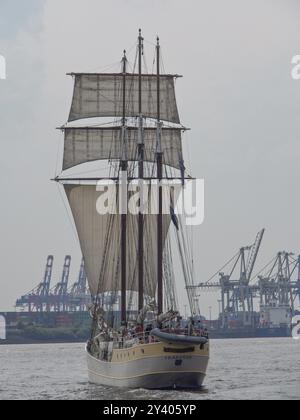 Un grand voilier navigue sur la mer, des grues portuaires peuvent être vues en arrière-plan, Hambourg, Allemagne, Europe Banque D'Images