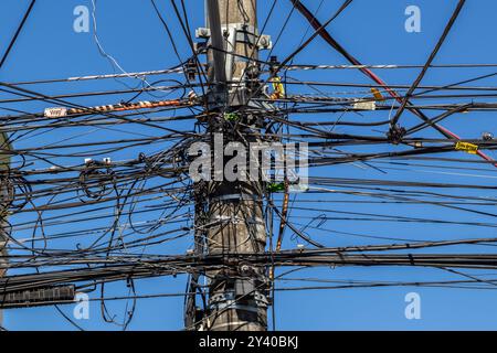 Marilia, SP, Brésil, 12 juin 2024. Beaucoup de fils attachés au poteau électrique, le chaos des câbles et des fils sur un poteau électrique, fond de ciel bleu, Banque D'Images