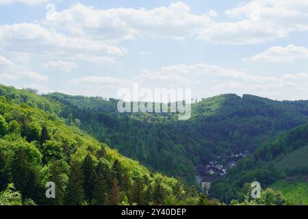 Des nuages épais blancs sur le ciel bleu flottent sur la surface verdoyante vallonnée et boisée de la terre. Belle photo de paysage de l'Allemagne Banque D'Images