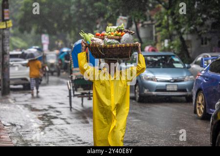 Un homme portant un imperméable marche sous la pluie dans les rues de Dacca. Banque D'Images