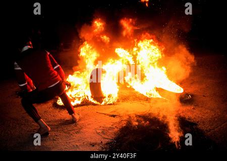 Gaza, Palestine. 24 avril 2021. Les Palestiniens brûlent des pneus et hissent le drapeau palestinien lors d'une manifestation à l'ouest de la ville de Gaza en soutien aux Palestiniens de Jérusalem-est. Depuis le début du Ramadan, le 13 avril, les tensions sont élevées à Jérusalem-est, dans un premier temps, à la suite de l'interdiction par les autorités israéliennes de se réunir autour de la porte de Damas, dans la vieille ville, où les Palestiniens ont tendance à se rassembler le soir pendant le Ramadan. Les tensions se sont encore aggravées jeudi soir lorsque des extrémistes juifs ont défilé près de la vieille ville de Jérusalem-est en scandant "mort aux Arabes" et en affrontant Banque D'Images