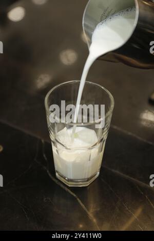 Lait froid versé dans un verre, prêt à compléter une dose d'espresso fraîche. Banque D'Images