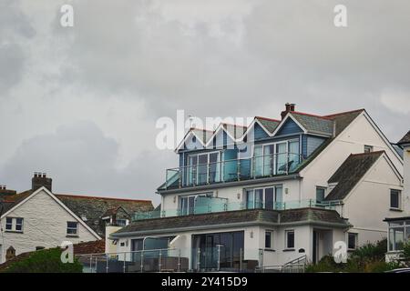 Une maison côtière moderne avec plusieurs balcons et de grandes fenêtres, posée contre un ciel nuageux. L'architecture dispose d'un design de toit unique et est surr Banque D'Images