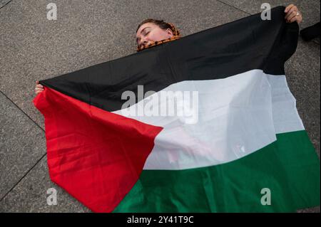 Madrid, Espagne. 15 septembre 2024. Une femme s'étend sur le sol avec un drapeau de la Palestine lors d'une manifestation de soutien au peuple palestinien. Les gens se sont rassemblés à Puerta del sol et ont effectué un couchage pour simuler les morts palestiniennes et pour exiger la fin des attaques israéliennes contre la bande de Gaza. Crédit : Marcos del Mazo/Alamy Live News Banque D'Images