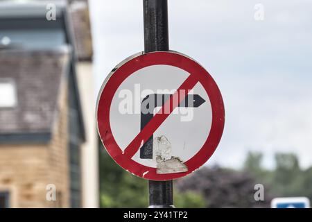 Un panneau de signalisation non virage à gauche altéré sur un poteau de rue, indiquant que les virages à gauche sont interdits. Le signe est partiellement endommagé, montrant des signes de wea Banque D'Images