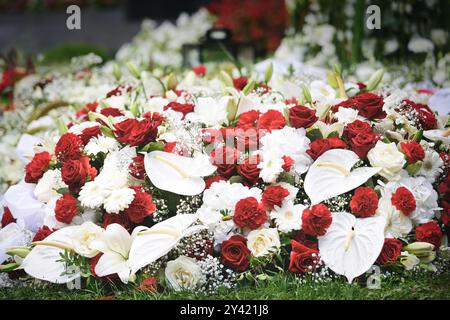 fleurs funéraires de roses rouges et œillets et fleurs blanches gerbera et flamant rose et gypsophila sur une tombe après un enterrement Banque D'Images