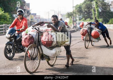 31 août 2024, Dhanbad, Jharkhand, Inde : des hommes poussent leurs vélos transportant des sacs de charbon le long d’une route, à la périphérie de Dhanbad. Jharia dans l'État indien de Jharkhand est le foyer d'environ 600 000 personnes. Il est situé au cœur du plus grand gisement de charbon du pays. Jharia, qui tire son nom de la ville et de la région du même nom, est également connue pour avoir un taux terrible d'incendies de veines de charbon, qui sont l'une des principales sources de pollution dans l'environnement à la fois localement et dans le monde entier. Des quantités massives de dioxyde de carbone sont libérées dans l'atmosphère par les feux de charbon. (Crédit image : © Banque D'Images