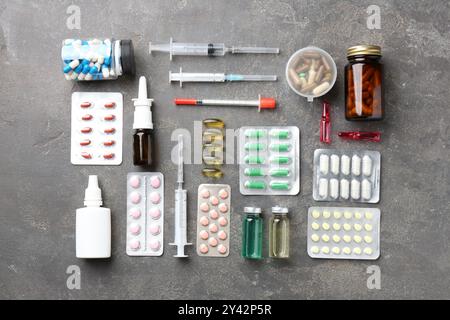 Pharmacien. Différentes pilules, seringues, flacons de gouttes médicales et ampoules sur table grise, pose à plat Banque D'Images