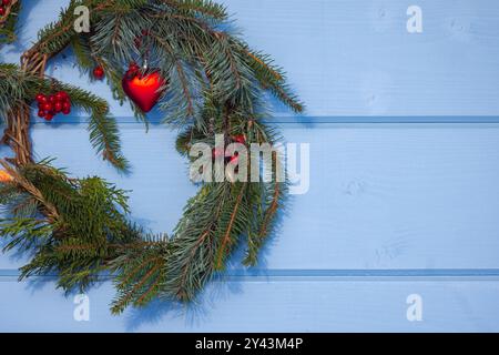 Couronne de Noël faite de branches d'épinette verte avec décoration accrochée sur un mur en bois bleu Banque D'Images