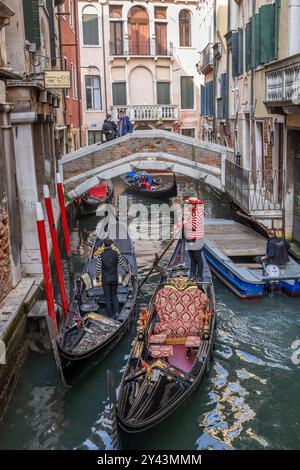 Venise, Italie - 20 mars 2024 - gondoles bateaux vénitiens traditionnels dans le canal Rio dei Bareteri, vue sur Ponte de le Acque dans le quartier de San Marco. Banque D'Images