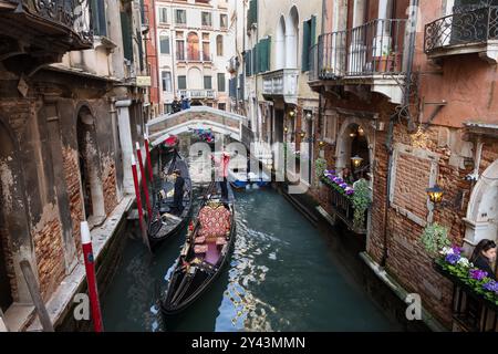 Venise, Italie - 20 mars 2024 - gondoles bateaux vénitiens traditionnels dans le canal Rio dei Bareteri, vue sur Ponte de le Acque dans le quartier de San Marco. Banque D'Images