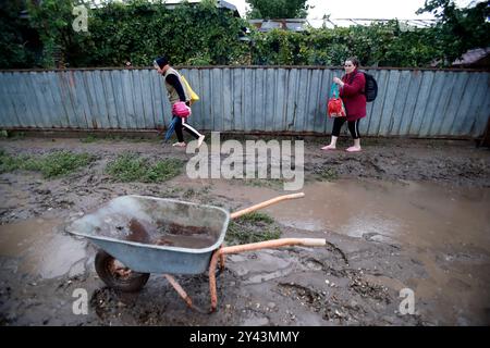 Galati, Roumanie. 15 septembre 2024. Les gens marchent sur une route boueuse après les inondations dans le comté de Galati, Roumanie, le 15 septembre 2024. Le comté de Galati, en Roumanie, peine à se remettre des graves inondations provoquées samedi par le cyclone Boris, qui a coûté la vie à cinq personnes et déplacé plus de 250 résidents. Crédit : Cristian Cristel/Xinhua/Alamy Live News Banque D'Images