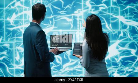 Équipe d'administrateurs utilisant une tablette et un ordinateur portable pour entretenir les réseaux neuronaux d'intelligence artificielle. Membres du personnel INFORMATIQUE travaillant en équipe utilisant un système d'IA aidant au traitement et à la transmission d'informations, caméra A. Banque D'Images