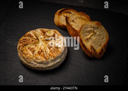 Camembert ou brie cuit au four sur fond noir avec du pain grillé ou du pain grillé. Copyspace. Photo de haute qualité Banque D'Images