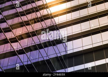 Fenêtres en verre réfléchissantes d'un bâtiment géométrique moderne à la lumière du soleil Banque D'Images