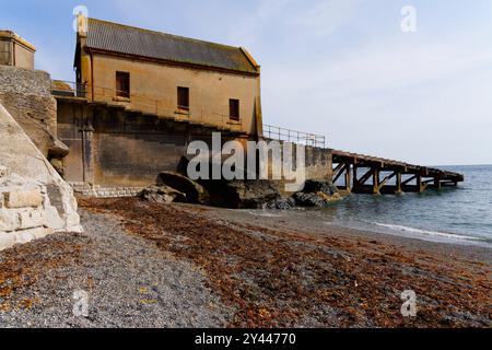 Sur la plage de Lizard point à Cornwall à marée basse regardant l'ancienne station de sauvetage désaffectée. Banque D'Images