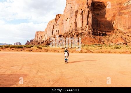 Femme dans une robe marchant vers Rain God Mesa dans Monument Valley. Banque D'Images