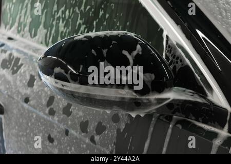 Auto recouvert de mousse de nettoyage au lavage de voiture, gros plan Banque D'Images