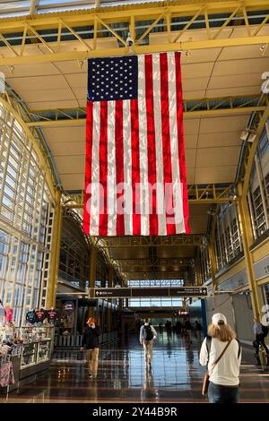 Un grand drapeau américain pend au plafond dans un bâtiment. Les gens se promènent dans la zone. Le drapeau est rouge, blanc et bleu. Ronald Reagan Washin Banque D'Images