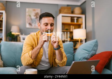Homme heureux faisant un achat en ligne à l'aide d'un ordinateur portable Banque D'Images