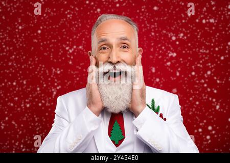 Photo de l'âge assez impressionné gentleman porter nouveau costume de l'année souriant bras joues isolé couleur rouge arrière-plan Banque D'Images