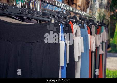 Collection colorée de pantalons suspendus avec des étiquettes de vêtements sur l'affichage dans le marché extérieur, divers modèles et couleurs, concept de mode au détail Banque D'Images